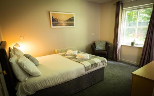 a bedroom with a bed and a chair and a window at Bunratty Castle Gardens Home in Bunratty