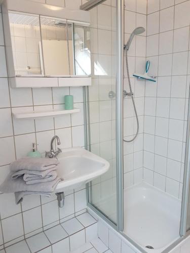 a white bathroom with a sink and a shower at Dat Inselhuus in Norden