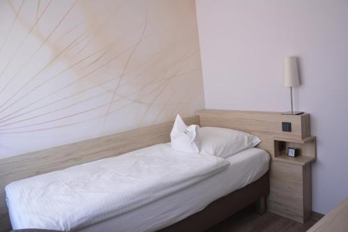 a bedroom with a white bed with a wooden headboard at Hotel Restaurant "Zur Post" in Holdorf