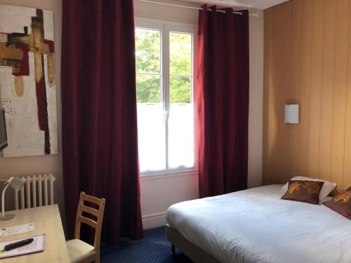 a bedroom with a bed and a window with red curtains at Hôtel Villa Du Parc in Nevers