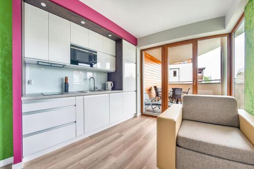 a kitchen with white cabinets and a couch in a room at Wczasowa, Sun & Snow in Ustka