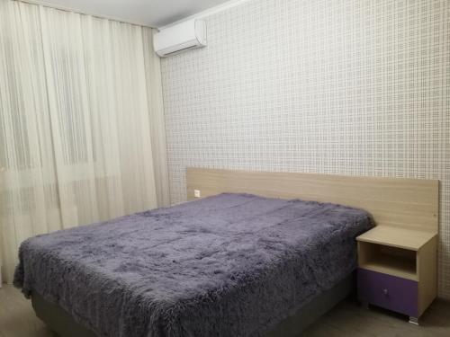 ノヴォロシースクにあるApartments Malaya Zemlya-2のベッドルーム1室(ベッド1台、紫の毛布付きのナイトスタンド付)