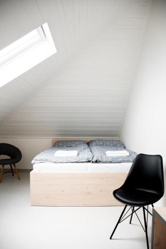 a bedroom with a bed and a black chair at Penzion Šafrán in Jeseník