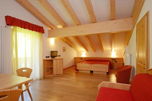 a bedroom with a bed and a table and chairs at Hotel La Soldanella in Moena