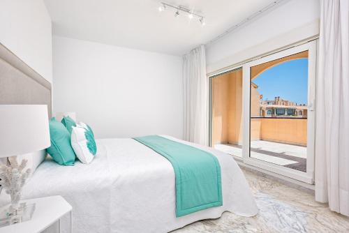 a white bedroom with a bed and a large window at Ático Playa de los Álamos in Torremolinos