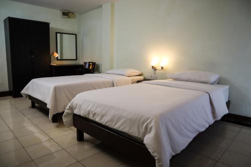 2 bedden in een hotelkamer met een spiegel bij Udoncabana in Udon Thani