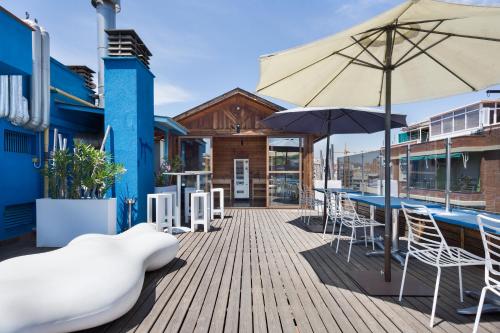 a deck with tables and chairs and an umbrella at Hotel Acta Azul Barcelona in Barcelona