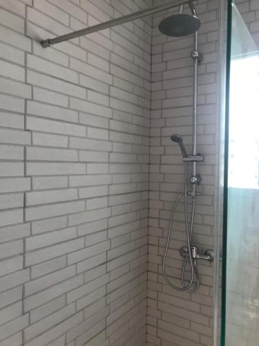 eine Dusche mit einer weißen Ziegelwand und einem Duschkopf in der Unterkunft Villa pilonga in Dos Hermanas
