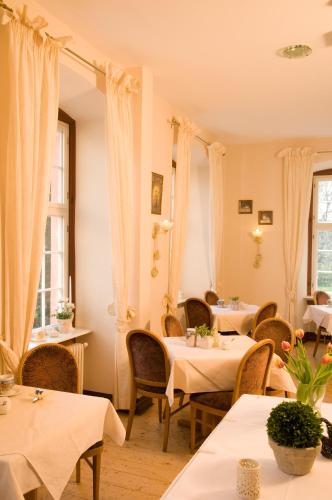 a restaurant with white tables and chairs and windows at SchlossHOTELGedern in Gedern