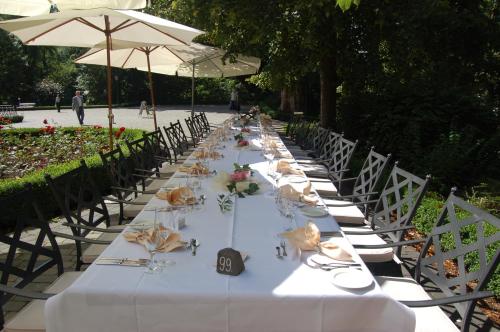 a long table with white tables and chairs and an umbrella at SchlossHOTELGedern in Gedern