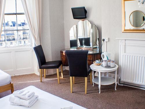 a living room filled with furniture and a tv at The Queensbury Hotel in Brighton & Hove