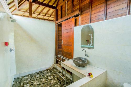 a bathroom with a stone sink and a shower at Mimpi Cottages in Nusa Lembongan