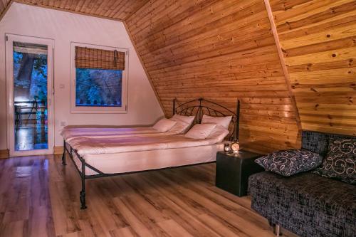 een slaapkamer met een bed en een bank in een kamer bij Jázmin Weekend House in Makó