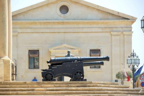a cannon in front of a building with a statue at Valletta Harbour View Apartment in Valletta