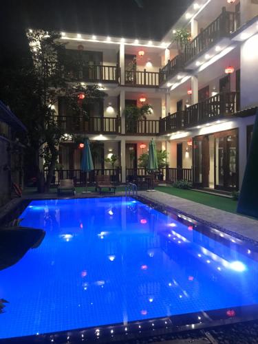 a large blue swimming pool in front of a building at Village Moon Villa in Hoi An