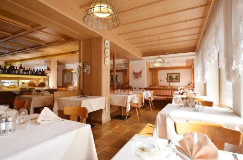 a restaurant with white tables and chairs in a room at Hotel La Soldanella in Moena