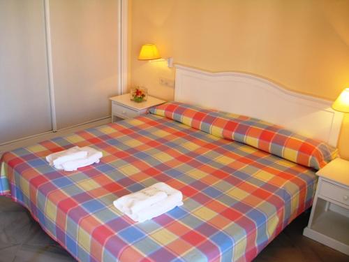 una camera da letto con un letto con due asciugamani sopra di Islantur Las Américas a Islantilla