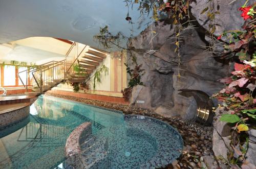 a swimming pool with a rock wall next to a poolasteryasteryasteryasteryastery at Hotel La Soldanella in Moena