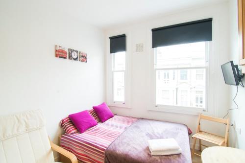 ロンドンにあるFairholme Studiosのベッドと窓が備わる小さな客室です。