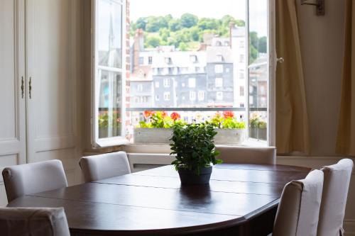 une table avec des chaises et une plante en pot devant une fenêtre dans l'établissement Appartement Vieux Bassin, à Honfleur