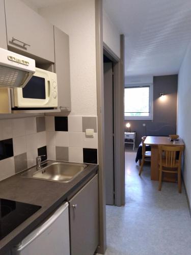a kitchen with a sink and a microwave at Pescalis Résidence Les Maisons du Lac in Moncoutant
