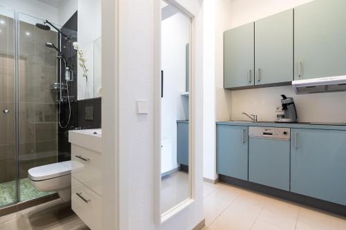 a bathroom with a toilet and a shower with blue cabinets at Freiburg Apartments Friedrichring in Freiburg im Breisgau