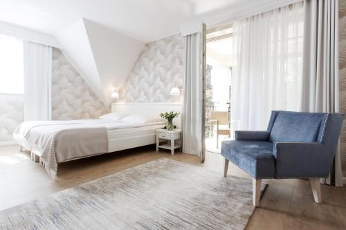 a bedroom with a bed and a blue chair at Hotel Villa Baltica in Sopot
