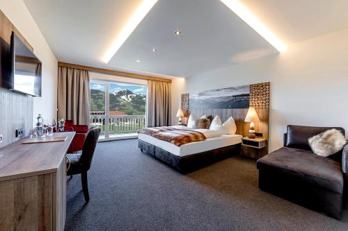 ホップフガルテン・イム・ブリクセンタールにあるLeamwirtのベッド、椅子、ソファが備わるホテルルームです。