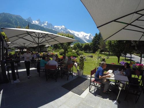 Un groupe de personnes assises à des tables sous des parasols dans l'établissement Hotel Le Castel, à Chamonix-Mont-Blanc