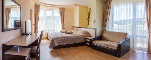 a bedroom with a bed and a chair and a desk at Семеен хотел "Елеганс" - Борино in Borino