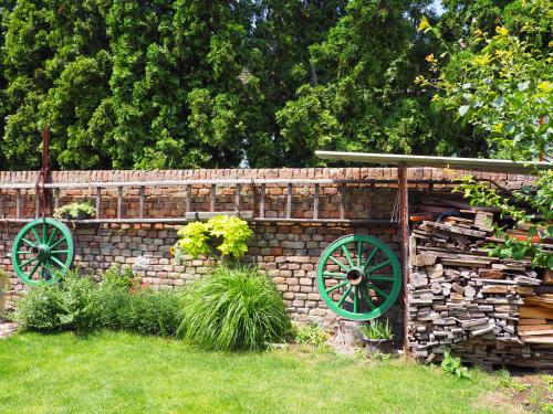 a brick fence with green wagon wheels in a yard at Penzion Pohoda in Lednice