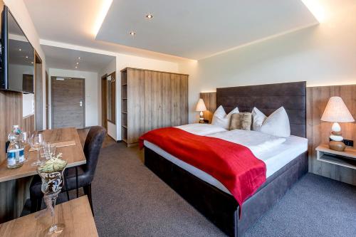 a hotel room with a large bed and a desk at Leamwirt in Hopfgarten im Brixental