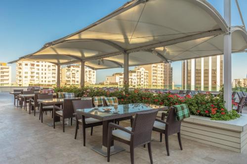 a patio area with tables, chairs and umbrellas at Point Hotel Baku in Baku