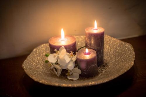 three candles on a plate with flowers on a table at VillAmour Boutique Hotel & SPA in La Salle