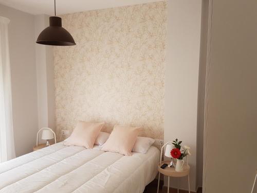 a bedroom with a large white bed with a wall at Apartamentos Los Corralejos in Fuengirola