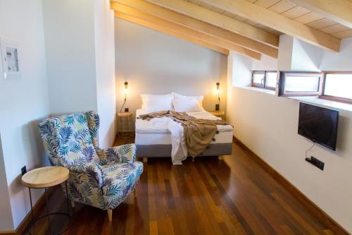 Sofita Hotel في بريفيزا: غرفة نوم بسرير وكرسي وتلفزيون