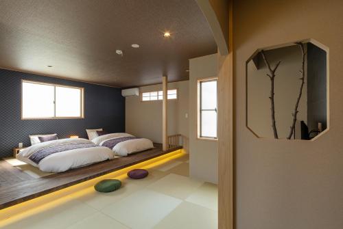 a bedroom with two beds and a tv on the wall at Hisashi in Kyoto