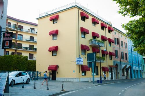 a large yellow building with red balconies on a street at Hotel Aurora in Desenzano del Garda