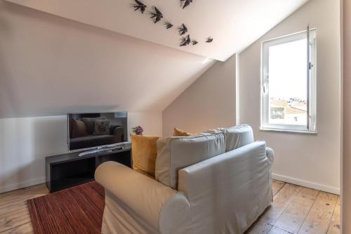 a living room with a white couch and a window at Carnot House in Setúbal
