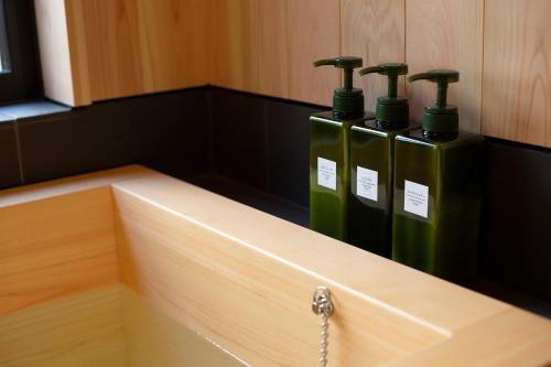 a row of three green bottles sitting on top of a counter at Hisashi in Kyoto