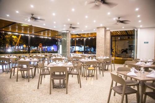 a restaurant with white tables and chairs and a view at Hotel Portobahia Santa Marta Rodadero in Santa Marta