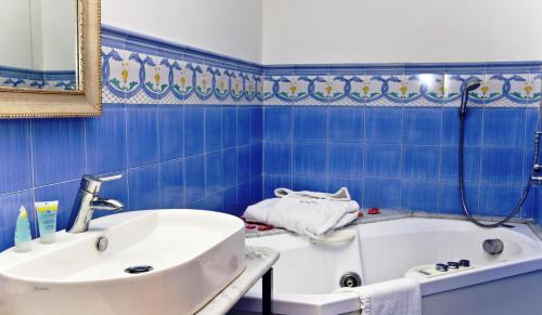 a blue bathroom with a tub and a sink at Punta Campanella Resort & Spa in Massa Lubrense
