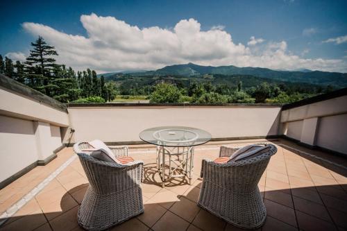 a balcony with a glass table and two chairs at Versilia Golf Resort in Forte dei Marmi