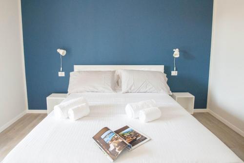 a white bed with two pillows and a magazine on it at Italianflat - Maison du Lac in Lazise