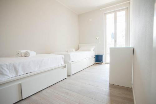 a white bedroom with two beds and a window at Italianflat - Maison du Lac in Lazise