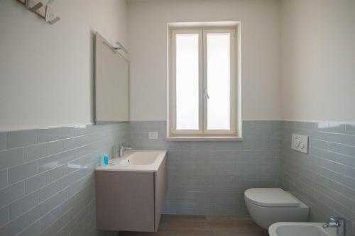 a bathroom with a sink and a toilet and a window at Italianflat - Maison du Lac in Lazise