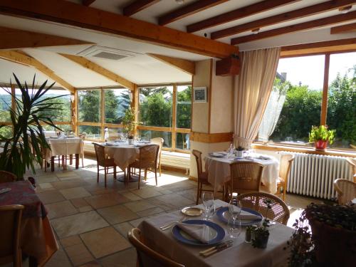 un restaurant avec des tables et des chaises et de grandes fenêtres dans l'établissement Hotel Les Chenets, à Saint-Julien-en-Champsaur