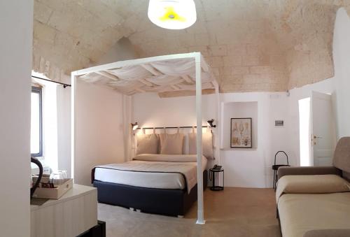 a bedroom with a canopy bed and a couch at GH Dimora Sant'Anna in Carovigno