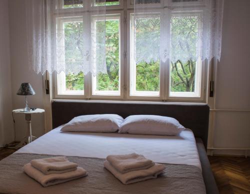 a bed with two towels on it in front of a window at Dunavski Park in Novi Sad