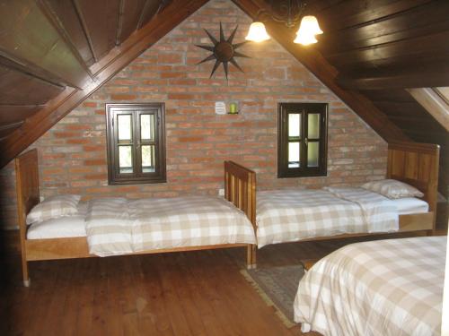 a attic room with two beds and a brick wall at Fürge Róka Porta in Őriszentpéter
